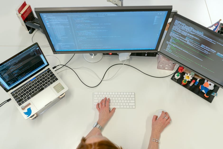 A female software engineer coding on dual monitors