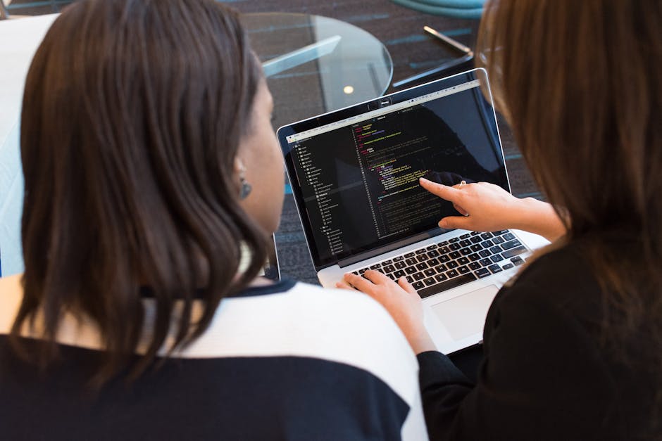 Two women working together on software programming indoors